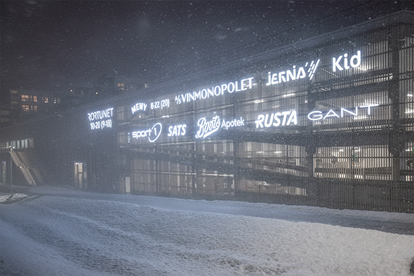 Lysskilt som lyser opp fasaden i vintermørket